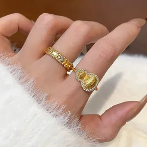Close-up detail of gold-plated gourd ring with sparkling cubic zirconia worn on index finger