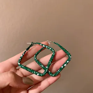 Macro view of retro green square hoop earrings featuring artistic white splatter pattern