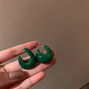 Hand-held detail of retro green marbled resin hoop earrings with silver needles