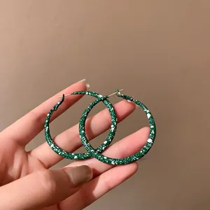 Macro view of vintage green hoop earrings featuring a unique white speckled pattern detail