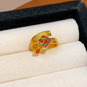 Detailed view of a gold-plated open ring featuring red enamel flower and lucky charms