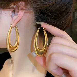 Eleganti orecchini a cerchio oversize in acciaio inossidabile dorato, su modella asiatica.