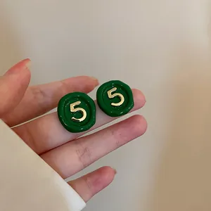 Detailed view of vintage green enamel stud earrings featuring a gold number 5 design