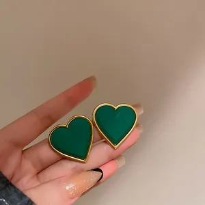 Detailed close-up of vintage green heart-shaped stud earrings with elegant gold border