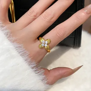 Close-up of elegant gold plated flower ring with sparkling cubic zirconia on finger.