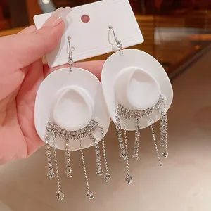 Dettaglio di orecchini a cappello da cowboy bianco con nappe in strass scintillanti