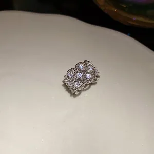 Detalle de un ear cuff plateado con circonitas y un intrincado diseño calado