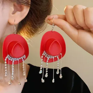 Dettaglio ravvicinato di orecchini a cappello da cowboy rosso con frange strass