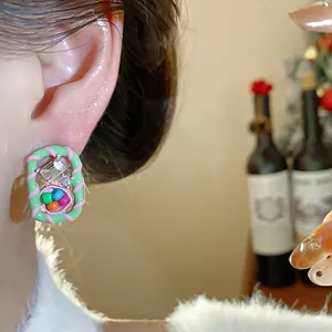 Close-up of a colorful dopamine style geometric earring with rhinestones worn on an ear