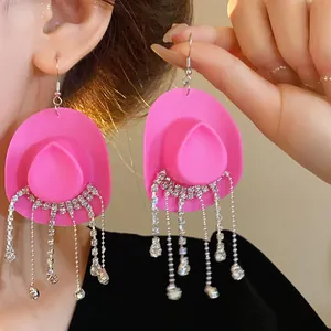 Dettaglio degli orecchini creativi a forma di cappello da cowboy rosa con strass