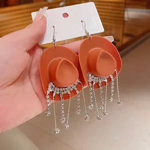 Dettaglio degli orecchini creativi a cappello da cowboy arancione con nappe di strass