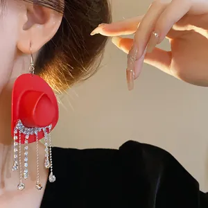 Dettaglio ravvicinato di orecchino a cappello da cowboy rosso con nappe di strass
