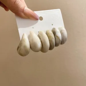 Detailed close-up of six marble-textured resin hoop earrings on a white display card.