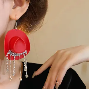 Dettaglio ravvicinato di orecchino a cappello da cowboy rosso con nappe di strass