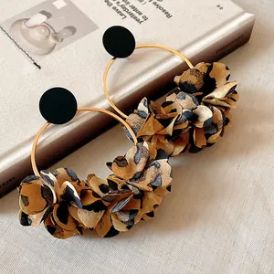 Dettaglio di orecchini a cerchio con petali leopardati vintage su un libro.