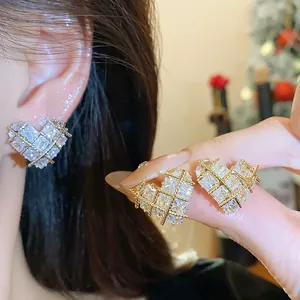 Détail de boucles d'oreilles cœur en zircone avec finition dorée sur la main et l'oreille