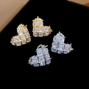 Gros plan d'élégantes boucles d'oreilles cœur en or et argent avec zircons étincelants.