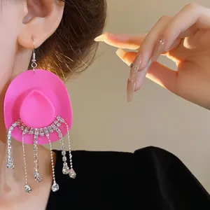 Primo piano di orecchini a cappello da cowboy rosa con nappe di strass brillanti.