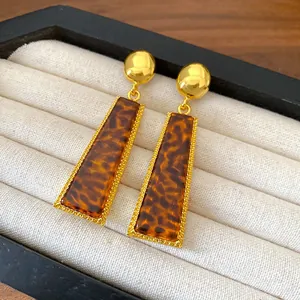 Dettaglio di orecchini vintage con stampa leopardata e bordi perlati color oro