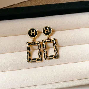 Primo piano di orecchini vintage leopardati dorati a forma rettangolare con logo H in un portagioie