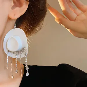 Dettaglio di un orecchino a cappello da cowboy bianco con nappe in strass