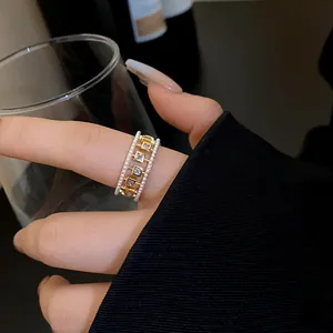 Close-up of a gold ring featuring delicate pearls and square-cut zircon stones