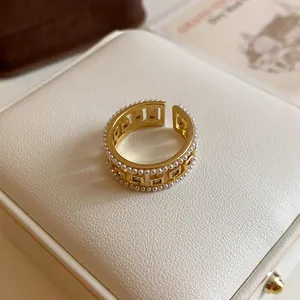 Close-up detail of a vintage gold open ring featuring square hollow zircon and pearls