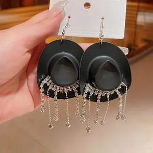 Primo piano di orecchini a cappello da cowboy neri con nappine di strass lucenti