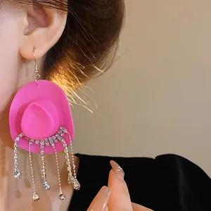Dettaglio di un orecchino creativo a cappello da cowboy rosa con nappe di strass brillanti