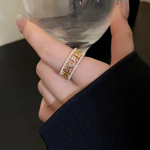 Elegant gold ring detail showing small pearls and square zircon hollow pattern on finger