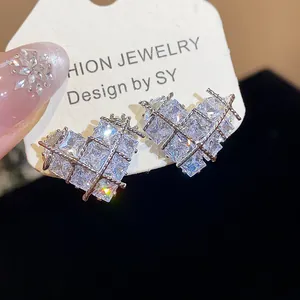Détail de boucles d'oreilles cœur en zircon avec motif de grille argentée