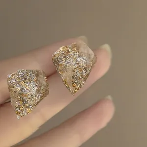 Macro detail of irregular resin stud earrings featuring gold and silver foil flakes.