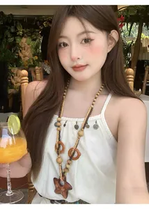 Dettaglio di una collana bohémien in grani di legno con ciondolo a stella su una modella