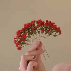 Detaillierte Nahaufnahme einer goldenen fächerförmigen Haarnadel mit zarten roten Blumen