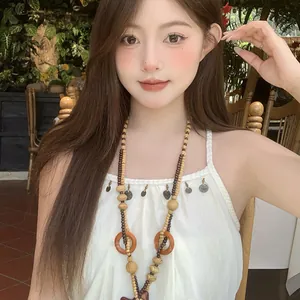 Dettaglio di collana bohémien con perle di legno e ciondolo a luna su modella