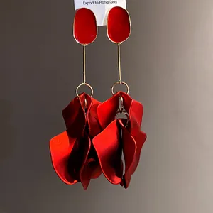 Detail view of retro red petal pendant earrings with gold-tone accents and oval studs