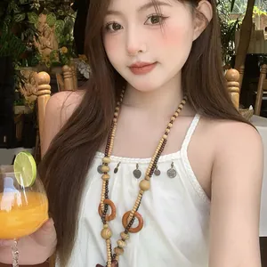 Dettaglio di una collana bohémien in legno su una modella in un contesto di vacanza