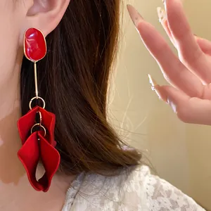 Close-up detail of elegant vintage red enamel petal drop earrings worn by a female model