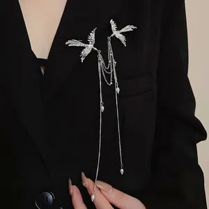 Elegant silver phoenix brooch with hanging pearls and tassels on a black blazer