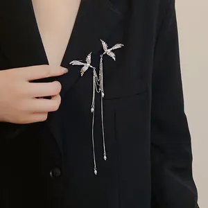 Detailed shot of a silver phoenix brooch with long pearl tassels on a black blazer