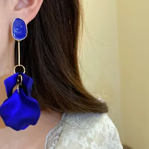Close-up of elegant blue oval enamel and fabric petal drop earrings worn by model