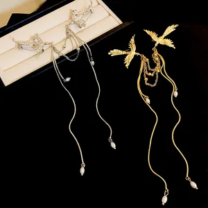 Macro detail of elegant gold and silver phoenix brooches featuring delicate pearl tassels
