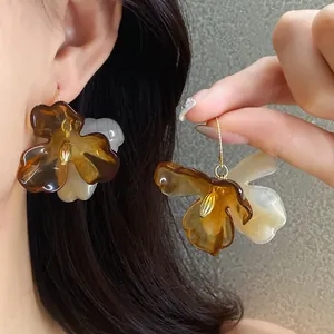Vue détaillée d'élégantes boucles d'oreilles fleurs en acrylique aux tons brun Maillard