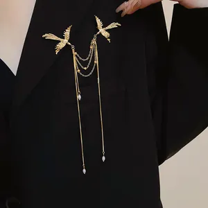 Detailed view of an elegant golden phoenix brooch featuring pearl tassels on a black suit