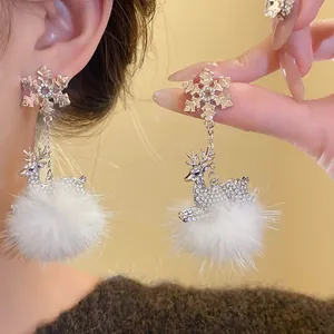 Dettaglio di orecchini in argento con fiocchi di neve e ciondoli a pompon di renna