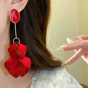 Close-up detail of elegant vintage red petal drop earrings with silver needle on model