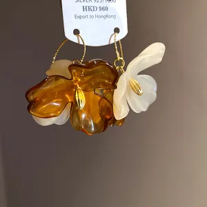Détail de boucles d'oreilles fleurs en acrylique style Maillard avec crochets en argent 925