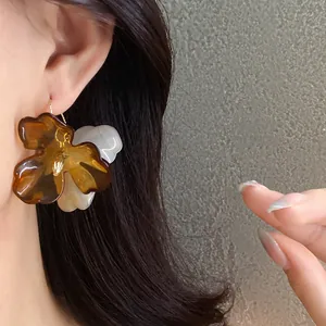 Gros plan détaillé montrant la texture des boucles d'oreilles fleur en acrylique