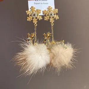 Dettaglio ravvicinato di orecchini a fiocco di neve dorati con renna di strass e pompon