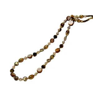 Elegant vintage tiger eye beaded necklace with golden metal and shell accents on white background